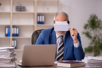 Aged male employee wearing virtual glasses in the office