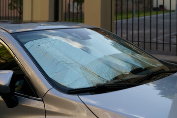Closeup of protective reflective surface under the windshield of the passenger car parked on a hot...