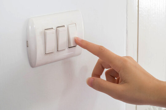 Hand push electric switch on white wall