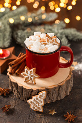 Red mug of hot cocoa with marshmallows and homemade Christmas gingerbread cookies. Christmas vertical card with hot cocoa and golden bokeh