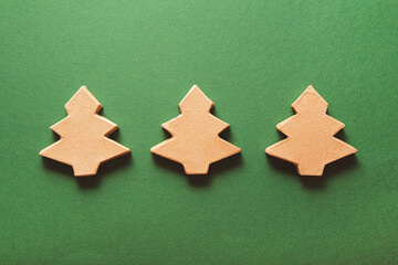 Three Christmas trees made of craft paper on a green background. Eco friendly new year and christmas concept
