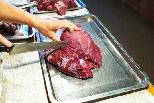 A merchant is cutting buffalo meat for sale.
