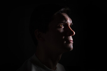 profile of thoughtful man looks to the right. portrait in side light, hard light, photo on black, looks up