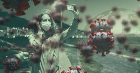 Covid-19 cells against woman wearing face mask taking a selfie