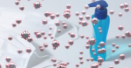 Fototapeta premium Covid-19 cells against bottle of sanitizer and face masks