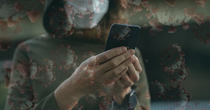 Covid-19 cells against woman wearing face mask using smartphone