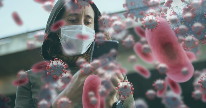 Covid-19 cells against woman wearing face mask using smartphone