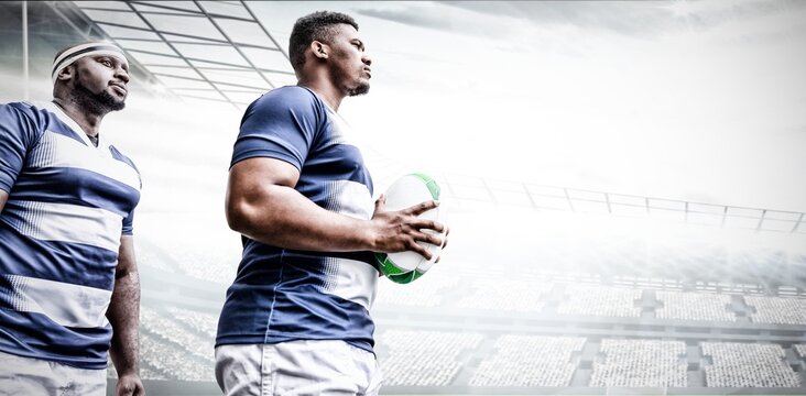 Digital composite image of two rugby players holding ball in sports stadium
