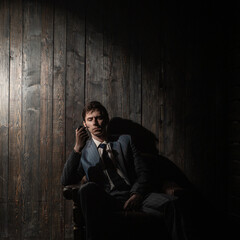 thoughtful man is sitting in an armchair and smoking, a portrait in semi-darkness with dark shadows, vintage noir style