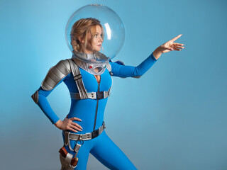 Fantastic astronaut costume in retrofuturism style. A young beautiful blonde in a blue suit with a spherical helmet. pioneer of space exploration, atomic era, retro style © Ulia Koltyrina