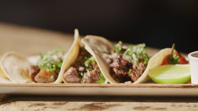Rack focus on restaurant plated gourmet Baja tacos in slow motion