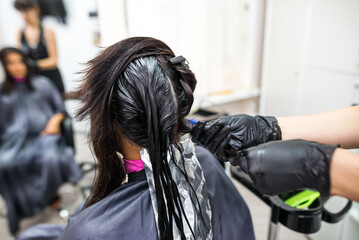 The hairdresser applies professional liquid keratin to the client's hair. A girl does keratin hair...