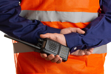 Torso of a worker in an orange reflective vest with a walkie-talkie in his hand, rear view. Selective focus isolated on white background