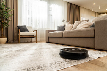 Cleaning with a robotic vacuum cleaner in a new living room in light beige and gray tones