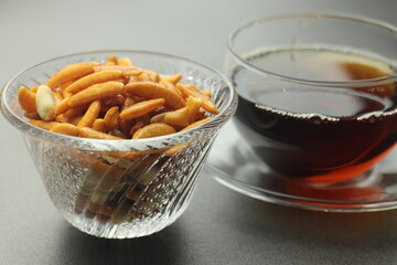 透明な皿に盛られた柿の種と紅茶