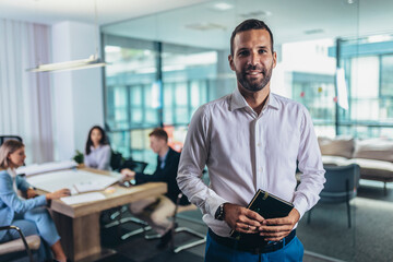 Portrait of a handsome young businessman in modern office smiling looking at the camera