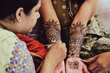 Master Applying henna tattoo on a bride hands. Elegant Brown Colors of Henna Ink. Indian Traitional...