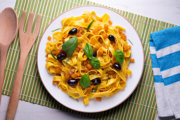 Pasta ribbons with sautéed pumpkin and black olives. Traditional Italian recipe.