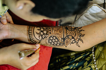 Applying henna tattoo on a bride hands. Elegant Brown Colors of Henna Ink. Indian Traitional Mehendi Ceremony.