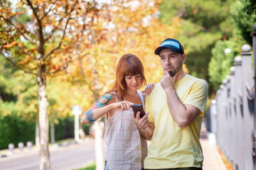 Fototapeta premium Caucasian woman with tattoos and pensive bearded man using a smartphone app with online map. Misunderstanding in a couple. The concept of relationship psychology and city trip