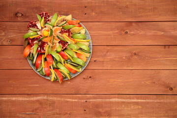 Obraz na płótnie Canvas The concept of assorted crushed apple fruits. Slice the pomegranate, lemon, kiwi, pear, orange and put it on a plate. fruit and vegetable salad. on a wooden background. space for text. Still life. 