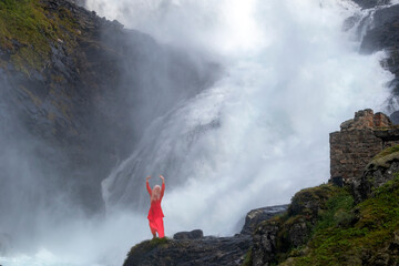 dancing girl in front of waterfall in flam , norway , The Flåm Line is a 20.2-kilometer long railway line between Myrdal and Flåm in Aurland Municipality, in Vestland county, Norway