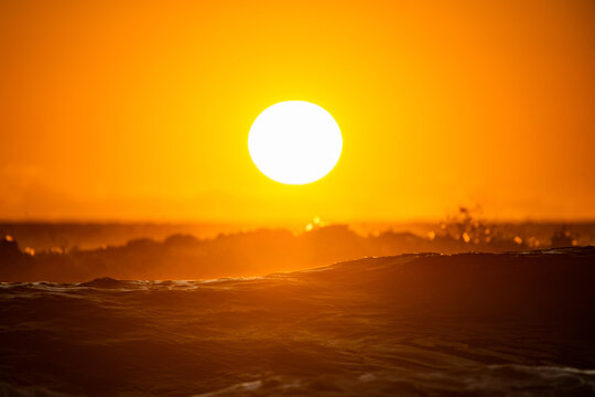 Horizontal shot of a rising sun above the ocean waves at sunrise