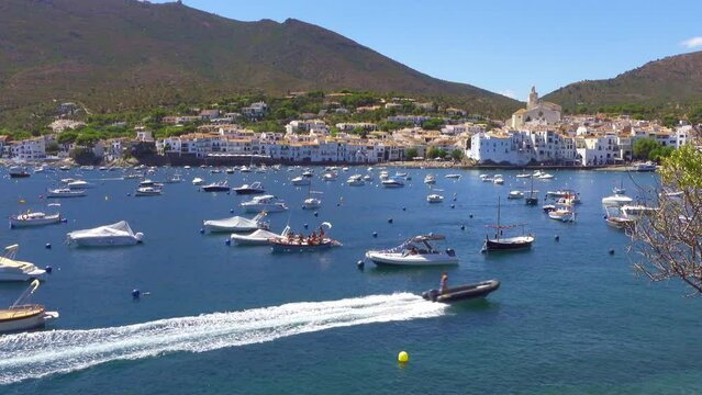 Outboard boat passing quickly between the boats docked in the cove of Cadaques, Girona, Spain.