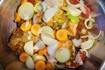 A raw sliced meat, pickled with spices, and vegetables for further cooking.