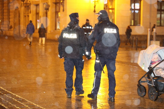 Polska policja na służbie zimą w czasie opad&oacute;w śniegu wieczorem. 