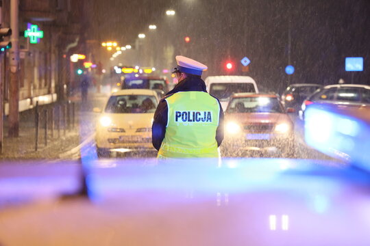 Polska policja na służbie zimą w czasie opad&oacute;w śniegu wieczorem. 