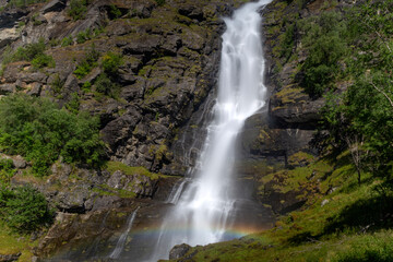 Fototapeta na wymiar waterfall with rainbow in the green mountains 