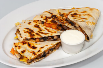 Quesadilla slices with mushrooms, sour cream and cheese on a white plate