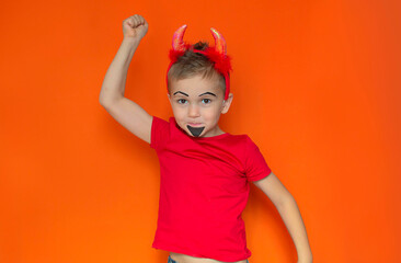 Funny children's portrait of a boy in a Halloween costume on an orange background. The boy is ready for the holiday of sweets