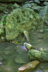 Naklejka na ściany i meble Big mossy stones in the rivers bed close-up
