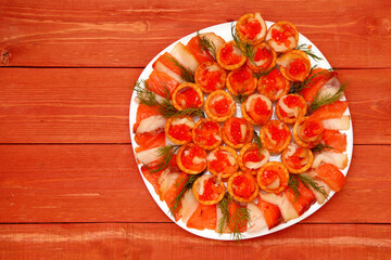 Tartlets with red caviar. Salmon caviar close-up. sliced white fish. Red fish. on a plate. Delicious food. The texture of caviar. Seafood appetizer. Grocery store. on a wooden background. space for te
