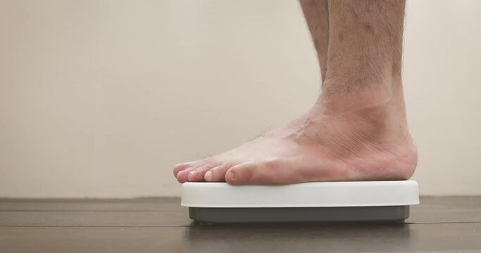 man step up to weight electronics scale to check BMI , weight loss and body health care concept