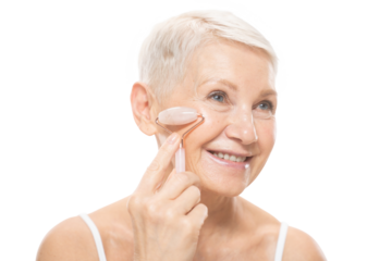 Beauty portrait of senior woman using facial roller massager for perfect skin on cheek