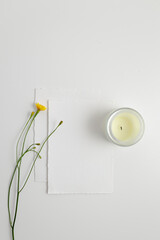 A business card and a candle are nearby