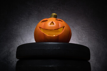 Small ceramic Halloween pumpkin on a dumbbell barbell weight plates. Healthy fitness lifestyle...