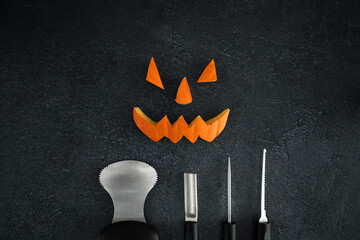 Halloween pumpkin cut out pieces. Spooky laughing, scary carved Jack Lantern eyes, nose, mouth. Jack-o'-lantern elements with carving tools - spoon, saw blade, pointed and grove carver.
