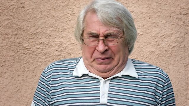Closeup portrait of old man, grandfather feeling disgusted and irritated isolated on concrete background. Senior man facial expression. Elderly Man with gray hair disliking something nasty and yucky.