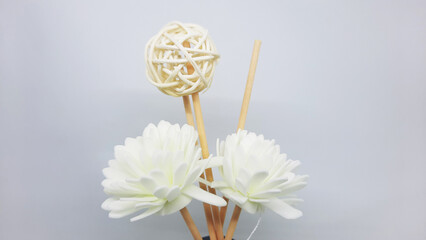 White flower decoration with rattan ball stick of a scented reed diffuser in transparent bottle
