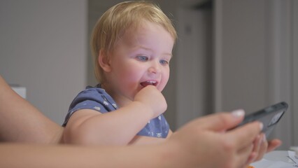 Happy Caucasian Toddler Baby Girl Watching Video and Playing on Smartphone with Mother Making Funny Faces and Showing Emotions