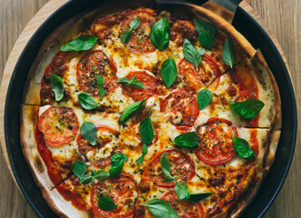 Tasty Homemade margherita pizza with with Tomatoes, Basil and Mozzarella Cheese on wooden background, top view.