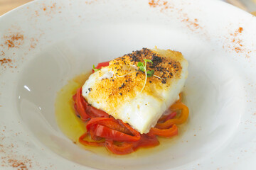 Delicious baked cod with roasted red pepper on wooden table.
