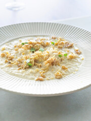 Delicious and creamy risotto dressed with cheese and walnuts on white plate. Top view and close up