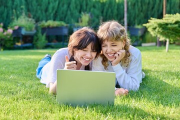 Fototapeta na wymiar Teenage female student friends laughing lying on grass with laptop