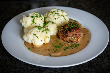 ready to eat - grilled venison burger from a charcoal grill with cauliflower, sauce and chives