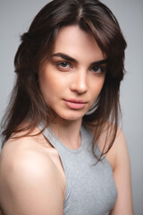 Naklejka premium Girl without makeup in a gray top on a light background